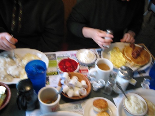 table at a diner w creamer and food and hands