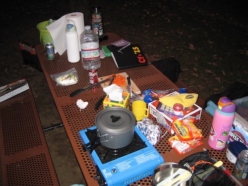 assorted objects on a picnic table at a campsite