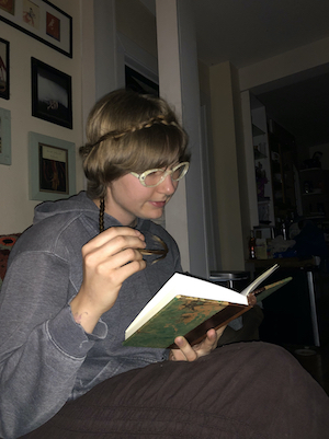 photo of cy holding a book and hair in their hand