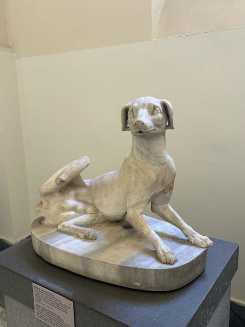 marble statue of a dog licking itself