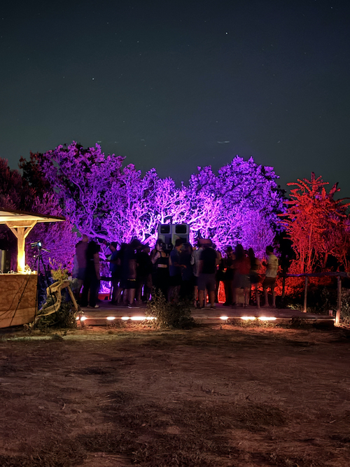 people dancing in front of a giant speaker w colorful lights behind them